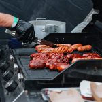 Grilling sausages on barbecue grill. BBQ in the garden. Street food festival